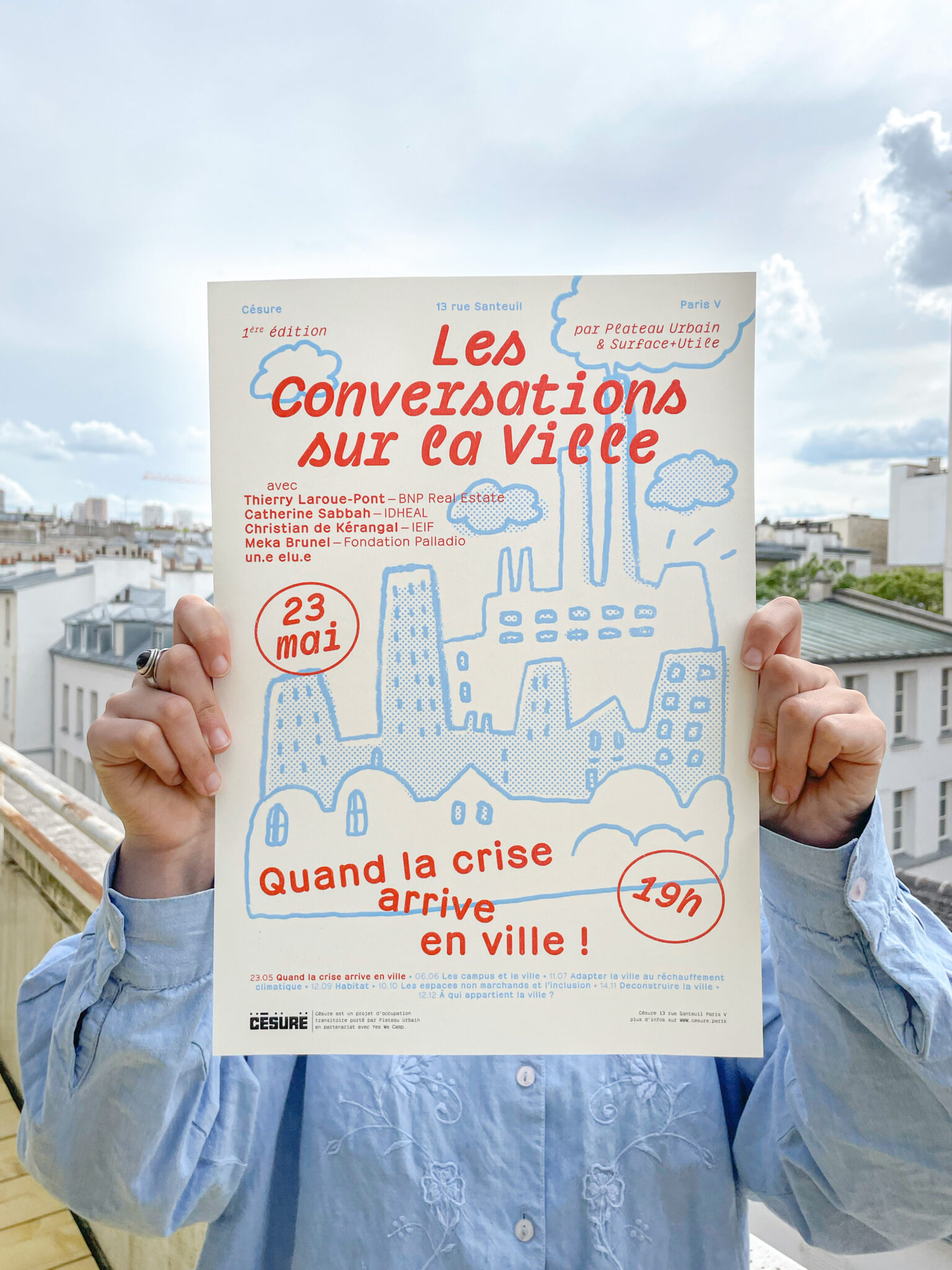 photographie d'une affiche, tenue par deux mains, présentant l'évènement Les Conversations sur la Ville.